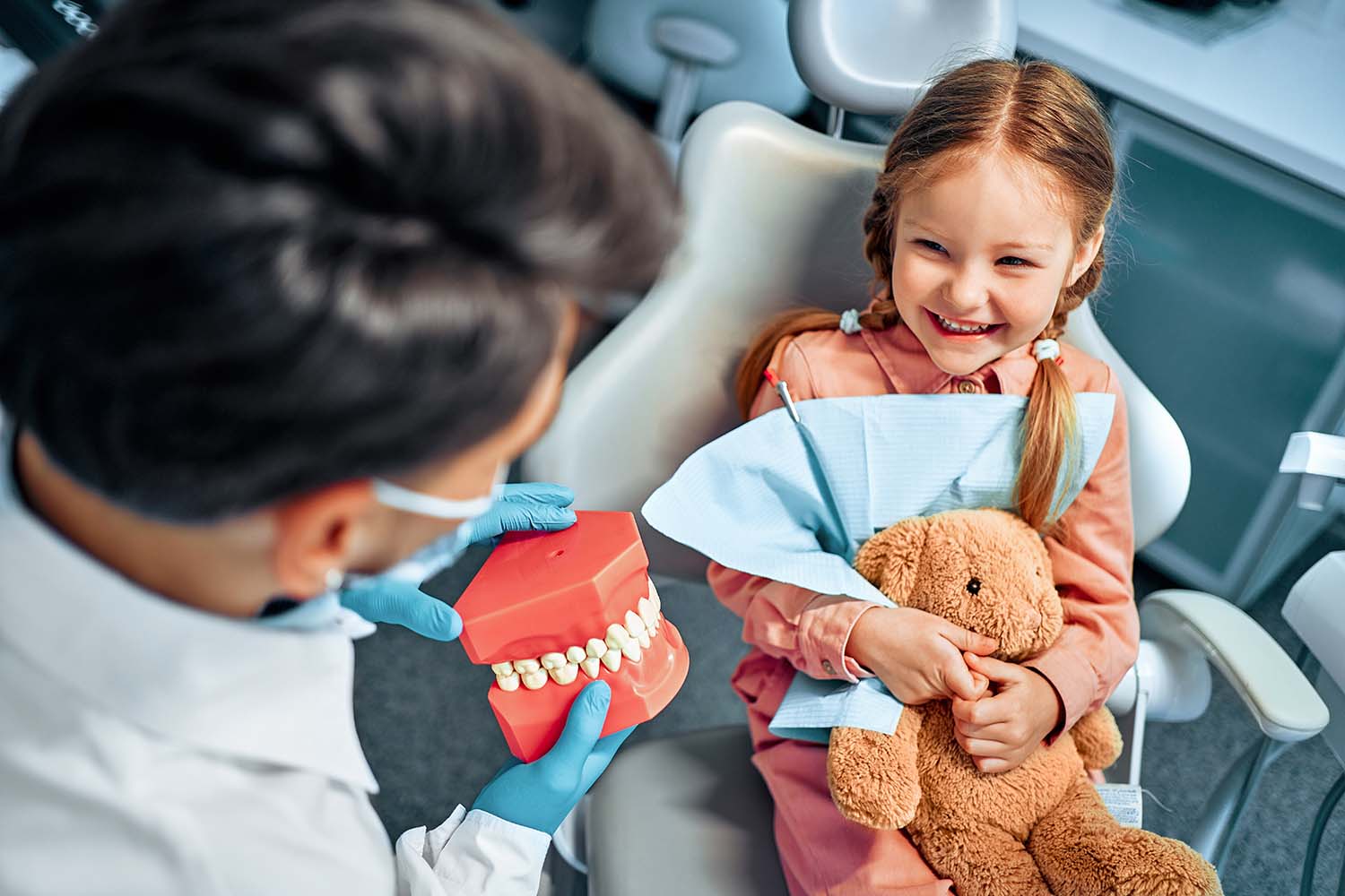 little girl sits dental chair holds