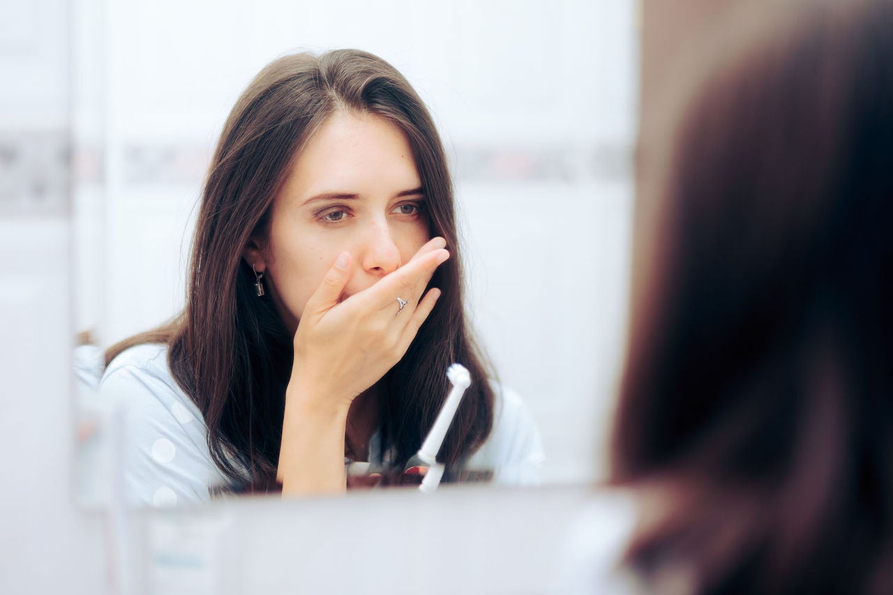 woman holding toothbrush having toothache looking
