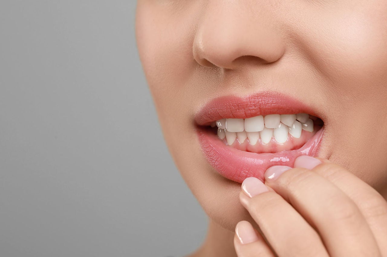 woman showing healthy gums on grey